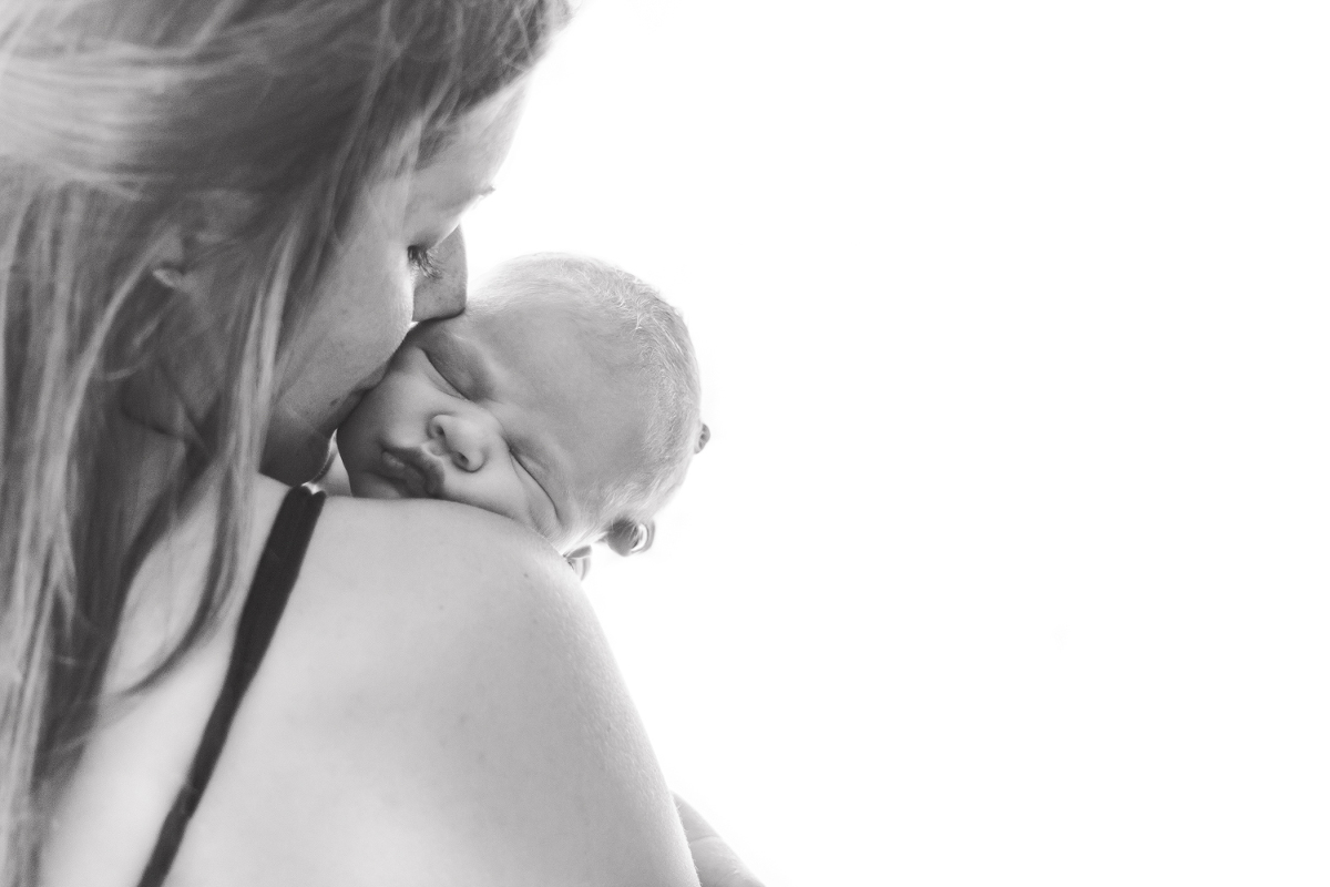 mom in front of window with newborn baby